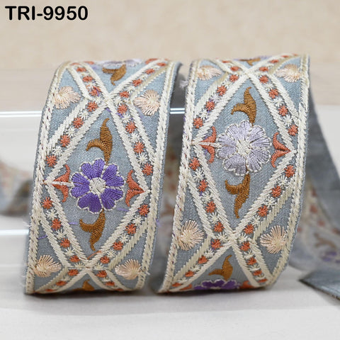 two decorative fabric pieces with intricate embroidered patterns in shades of blue, purple, and orange. The patterns include flowers and geometric designs, creating a visually appealing and textured appearance.