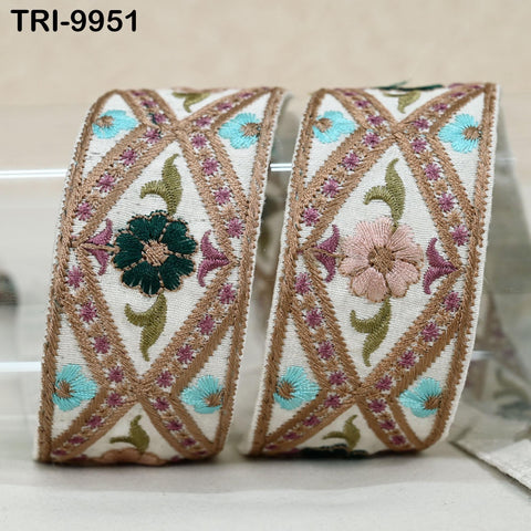 two decorative fabric pieces with intricate embroidered patterns in shades of green, pink, and brown. The patterns include flowers and geometric designs, creating a visually appealing and textured appearance.