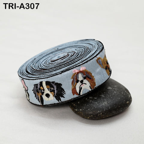 A blue and white dog embroidered ribbon is rolled up and placed on a black rock.