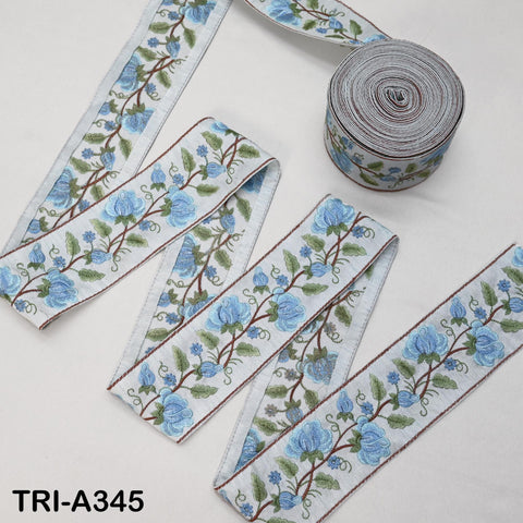 a collection of decorative fabric pieces, including a spool of embroidered fabric and several pieces of fabric with a floral pattern.