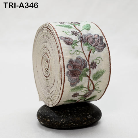 A decorative fabric with a floral pattern, including purple and green flowers, is rolled up and displayed on a black rock.