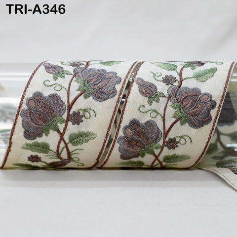 a decorative fabric with a floral pattern, featuring a repeating design of purple flowers and green leaves. The fabric appears to be a ribbon or a piece of cloth with a similar pattern.