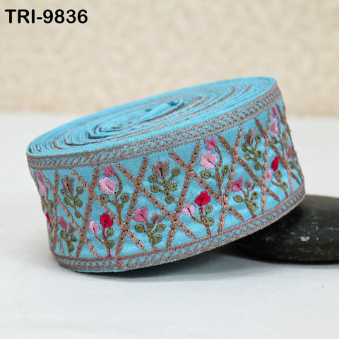 A blue fabric with a floral pattern, featuring pink and green flowers, is displayed on a white surface.