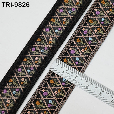 a decorative black and gold embroidered ribbon with a ruler placed on top of it, indicating its size.