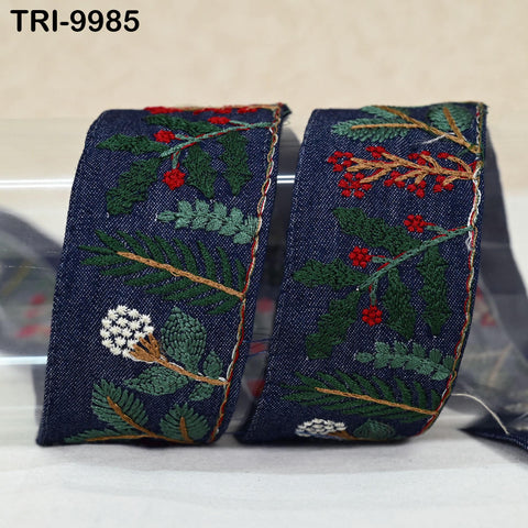a pair of blue denim fabric pieces with intricate embroidered designs of leaves, flowers, and berries.