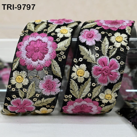 two decorative fabric pieces with a floral pattern in shades of pink and yellow. The pieces appear to be made of a shiny material, possibly silk or lace, and are displayed on a surface.
