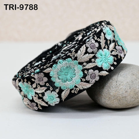 A close-up image of a decorative fabric with a floral pattern in shades of blue and green, resting on a white surface.