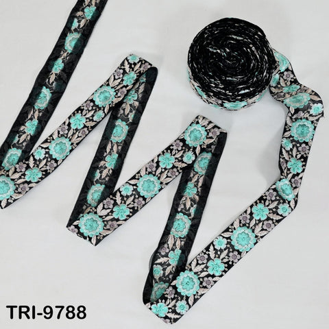 a spool of black and white floral embroidery thread and a spool of turquoise floral embroidery thread, both with a floral pattern.
