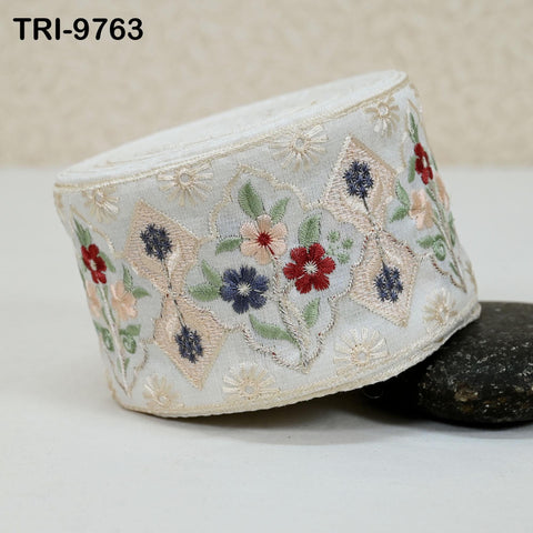 a decorative fabric with a floral pattern, including red, blue, and green flowers, as well as leaves, arranged in a circular or oval shape.