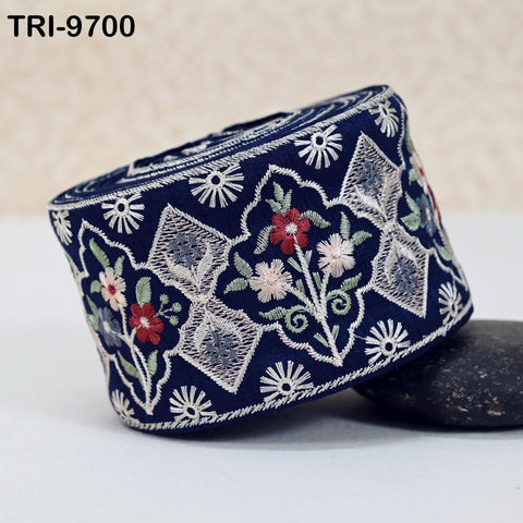 a decorative blue and white fabric with floral patterns and designs, including flowers and leaves, arranged in a circular pattern.