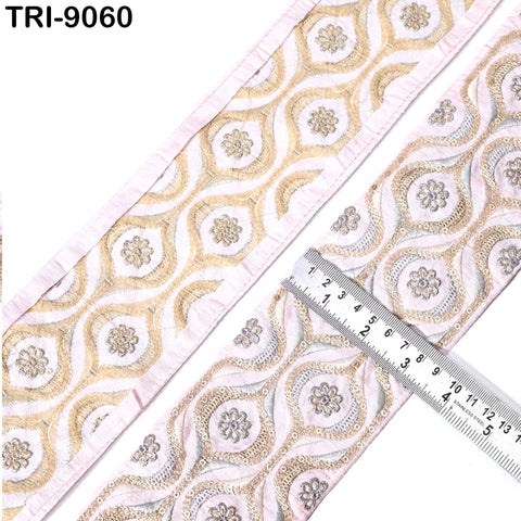 a close-up view of a decorative fabric with a repeating pattern of floral designs in shades of pink and gold. A ruler is placed on the fabric, indicating its size or dimensions.