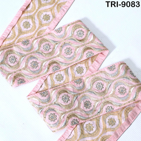 a decorative fabric with a repeating pattern of pink and gold floral designs. The fabric appears to be a decorative textile, possibly used for clothing or home decor.