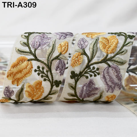 a decorative fabric with a floral pattern, including yellow and purple flowers, and green leaves. The fabric appears to be a ribbon or a piece of cloth with a floral design.