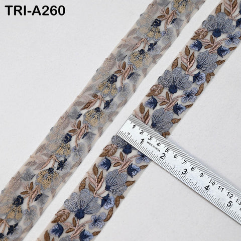 two spools of embroidered fabric with a floral pattern, placed next to a ruler for size comparison.