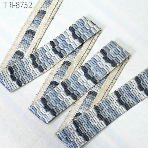 a close-up view of a decorative fabric with a repeating pattern of blue and gray geometric shapes. The fabric appears to be a type of textile or textile-like material, possibly used for clothing or home decor.