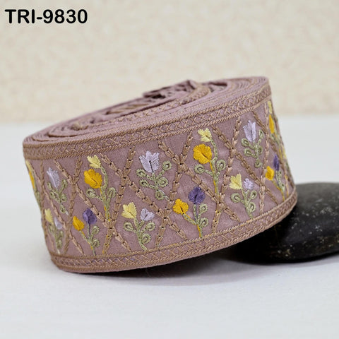 A decorative fabric with a floral pattern, featuring a combination of purple, yellow, and green flowers, is displayed on a white surface.