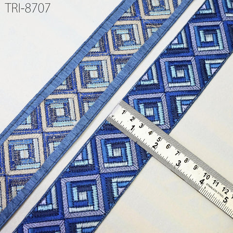 a close-up view of a blue and white geometric patterned fabric, with a ruler placed on top of it to measure its dimensions.