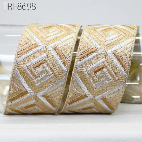 two pieces of decorative fabric with a geometric pattern in shades of gold and white.