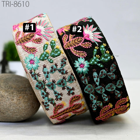 Two colorful, embroidered headbands are displayed, one with a floral pattern and the other with a cactus pattern, both featuring a variety of flowers and leaves.