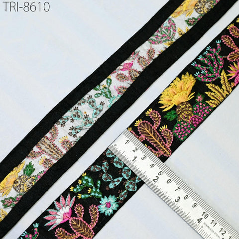 a close-up view of a decorative fabric with a floral pattern, featuring a black border and a ruler for size reference.