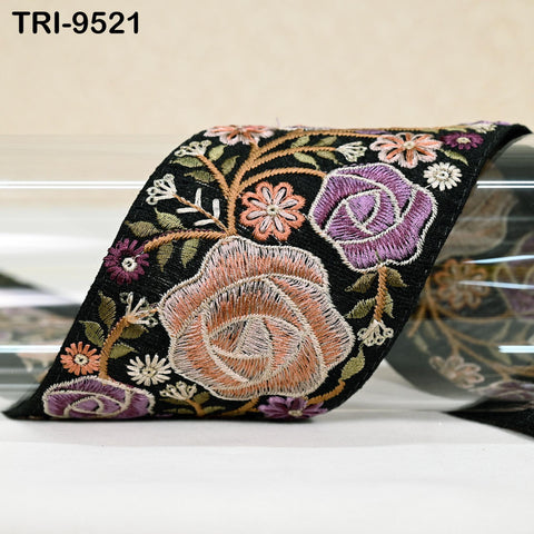 a decorative fabric with a floral pattern, including roses and other colorful flowers. The fabric appears to be black and has a textured appearance.