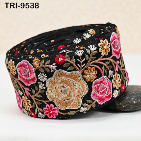 a black fabric with a floral pattern, including pink and yellow flowers, as well as other decorative elements.