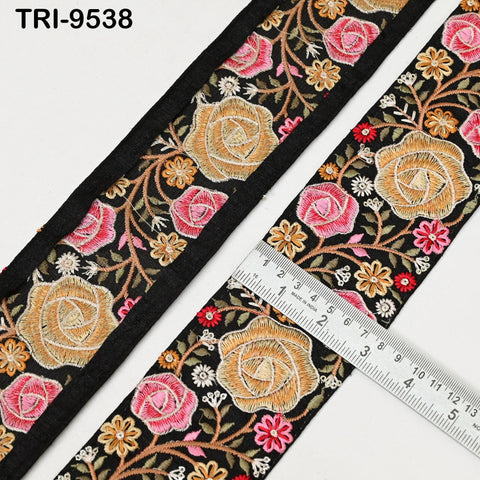 a close-up view of a decorative fabric with a floral pattern, featuring a black border and a ruler for size reference.