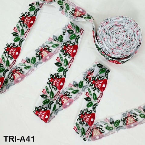 a spool of red and white floral fabric, along with a spool of white fabric with red and green floral patterns, both placed on a white surface.