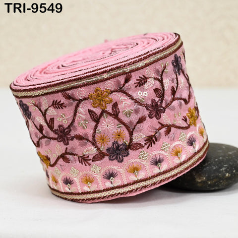 A pink fabric with a floral pattern, featuring a variety of colors including pink, purple, and yellow flowers, is displayed on a white surface.
