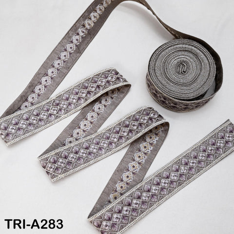 a collection of decorative fabric pieces, including a spool of gray fabric with a repeating pattern of purple and white flowers, as well as several pieces of fabric with a similar pattern.