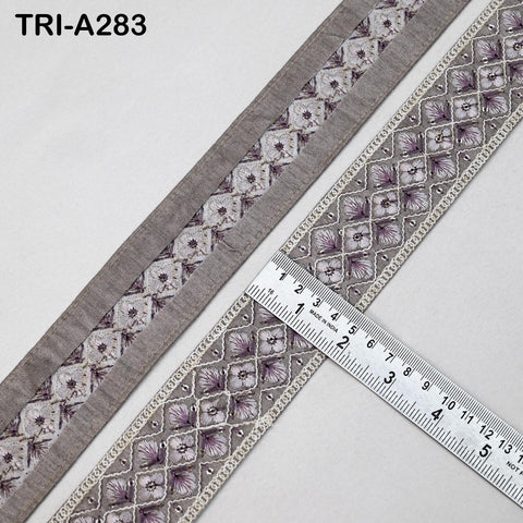 a close-up view of a decorative fabric with a repeating pattern of purple and white flowers. A ruler is placed on top of the fabric, indicating the size or dimensions of the pattern.