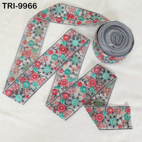 a collection of decorative fabric pieces, including a floral-patterned ribbon and a spool of thread with a similar floral design.
