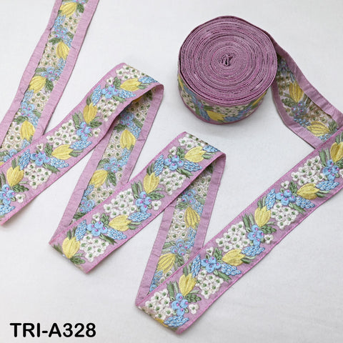 a spool of purple fabric with a floral pattern and two spools of fabric with similar floral patterns, all placed on a white surface.