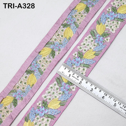 a close-up view of a decorative fabric with a floral pattern, including yellow and blue flowers, placed next to a ruler for size comparison.