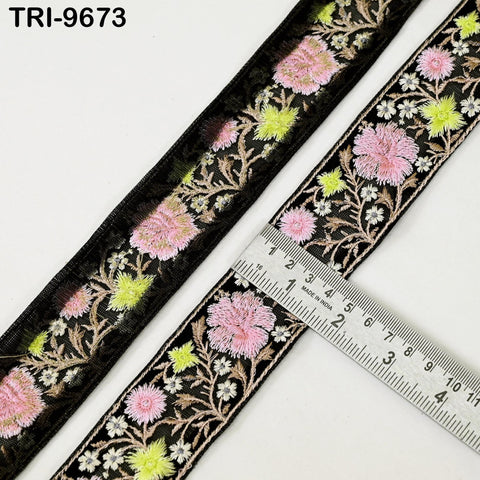a close-up view of a decorative fabric with a floral pattern, featuring a black border and pink and yellow flowers. A ruler is placed next to the fabric, indicating the size of the fabric.