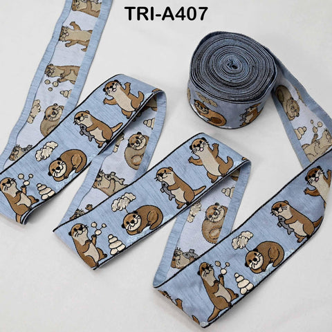 a collection of blue fabric ribbons with a repeating pattern of cartoon otters. The ribbons are arranged in a way that they appear to be rolled up or coiled, with one ribbon in the foreground and several others in the background.