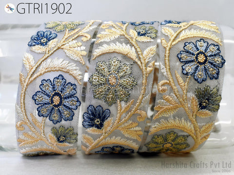 a close-up view of a decorative fabric with intricate floral embroidery in shades of blue and gold.