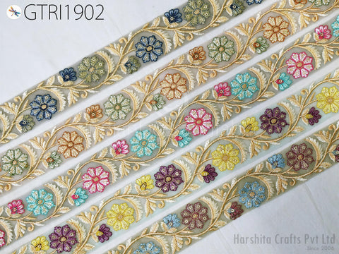 a decorative fabric with a repeating floral pattern in various colors, including blue, green, yellow, and purple. The pattern is composed of multiple rows of flowers and leaves, creating a visually appealing and intricate design.