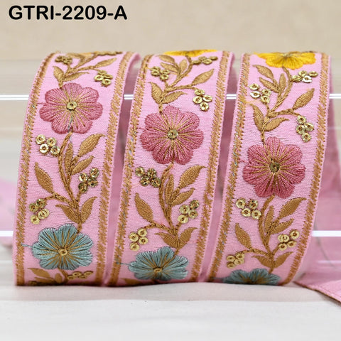 a close-up view of a pink fabric with gold embroidered flowers and leaves.
