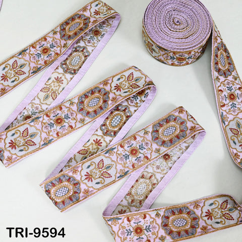 several rolls of decorative fabric with intricate floral patterns in shades of pink and purple. The rolls are arranged on a white surface, with one roll placed on top of the others.