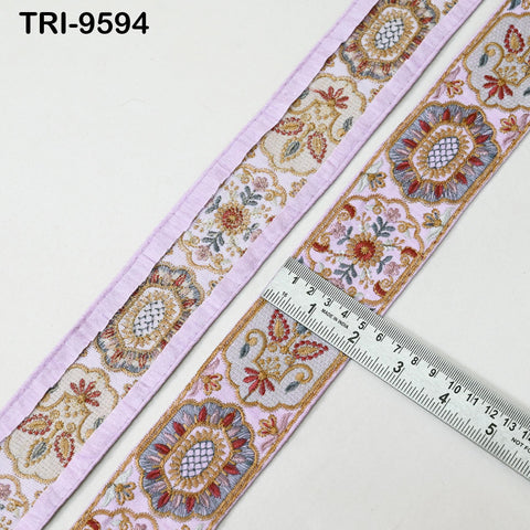 a close-up view of a decorative fabric with a floral pattern, placed next to a ruler for size comparison.