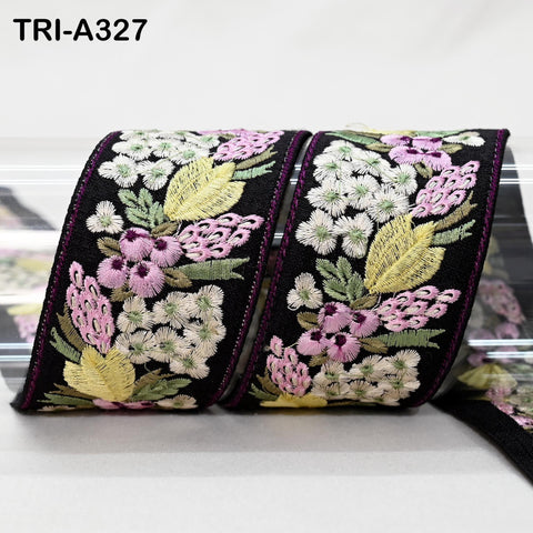 a decorative floral embroidered fabric, with a black border and a variety of colorful flowers and leaves.