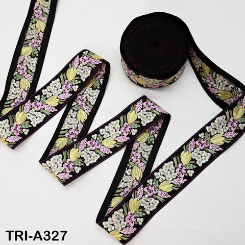 a spool of black and pink embroidered fabric, with a floral pattern, and a piece of the fabric lying on a white background.