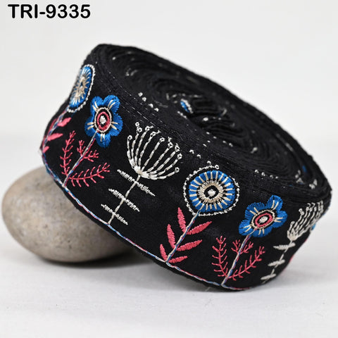 a black fabric with a floral pattern, including blue and pink flowers, on a white background.