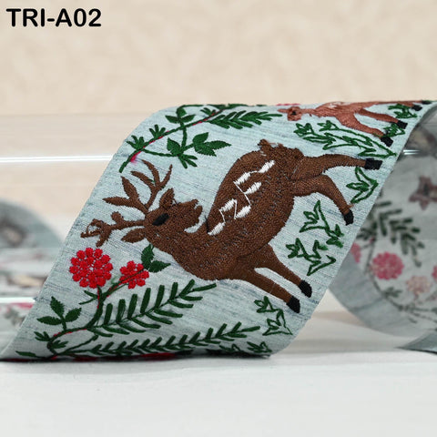 a decorative fabric with a brown deer embroidered on it, surrounded by green leaves and red flowers.