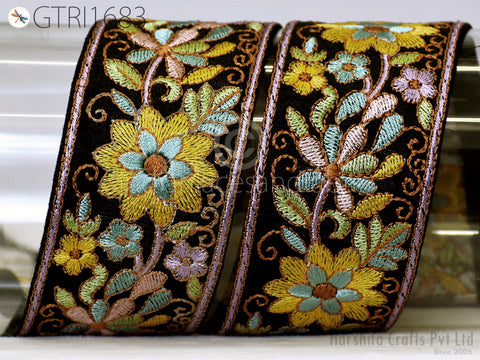two ornate, decorative fabric pieces with intricate floral embroidery in various colors, including yellow, green, and purple. The pieces appear to be made of a shiny, black material and are displayed against a plain background.