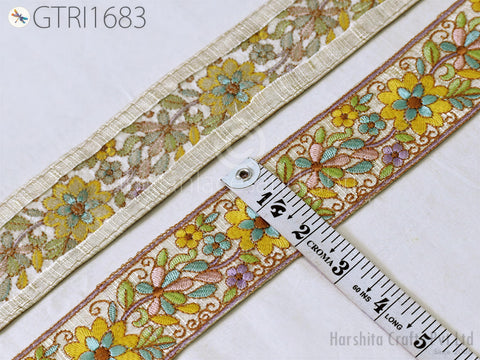 a close-up view of a decorative fabric with a floral pattern, featuring a measuring tape placed on top of it.