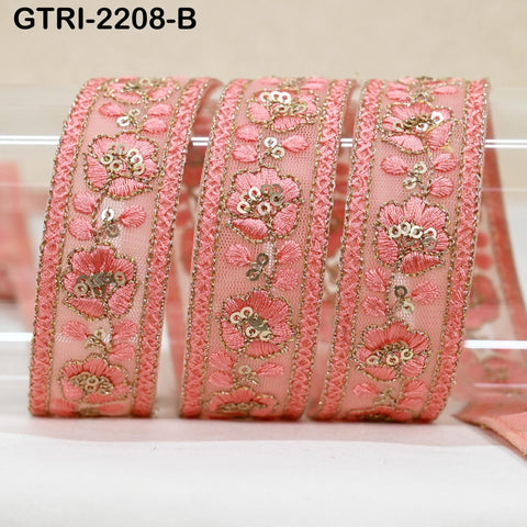 A close-up image of a decorative pink fabric with intricate floral embroidery and sequin embellishments.