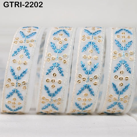 A close-up image of a white ribbon with a blue and gold floral pattern, arranged in a row.