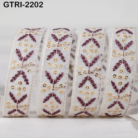 A close-up image of a decorative ribbon with a repeating pattern of purple and gold designs.